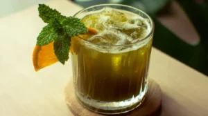 Chilled Japanese Mounjaro detox tea in a glass with mint and orange slice on a wooden table