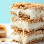 Three Rice Krispie ice cream sandwiches stacked with vanilla ice cream melting between the cereal layers