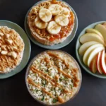 A flat lay of easy no-fridge dorm recipes on a small dorm table: rice cakes with peanut butter and banana, instant ramen with canned veggies, apple slices with peanut butter drizzle, and a couscous bowl. Bright, colorful, appetizing presentation.
