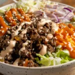 Big Mac burger bowl with lettuce, beef, cheese, pickles, and sesame seeds.