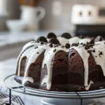 Full Oreo bundt cake topped with glaze and crushed cookies in a cozy student kitchen