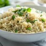 Perfectly cooked fluffy quinoa in a white bowl with herbs, photographed for a student-friendly cooking guide.