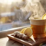 Hot non alcoholic grog with lemon, honey, and ginger on a wooden tray in natural light.