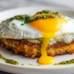 Golden pesto egg on crispy hash brown, minimalist white background, bright student breakfast.