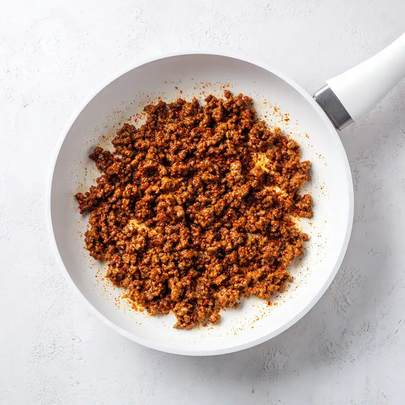 Taco Bell Mexican Pizza Recipe (Cheap, Easy & Better Than Takeout!) 4 Seasoned ground beef cooking in a white pan on a clean bright white surface.