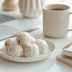 A bright photo of easy sweets milk balls on a white desk beside a student’s laptop, showing a cozy dorm setup with natural white light.