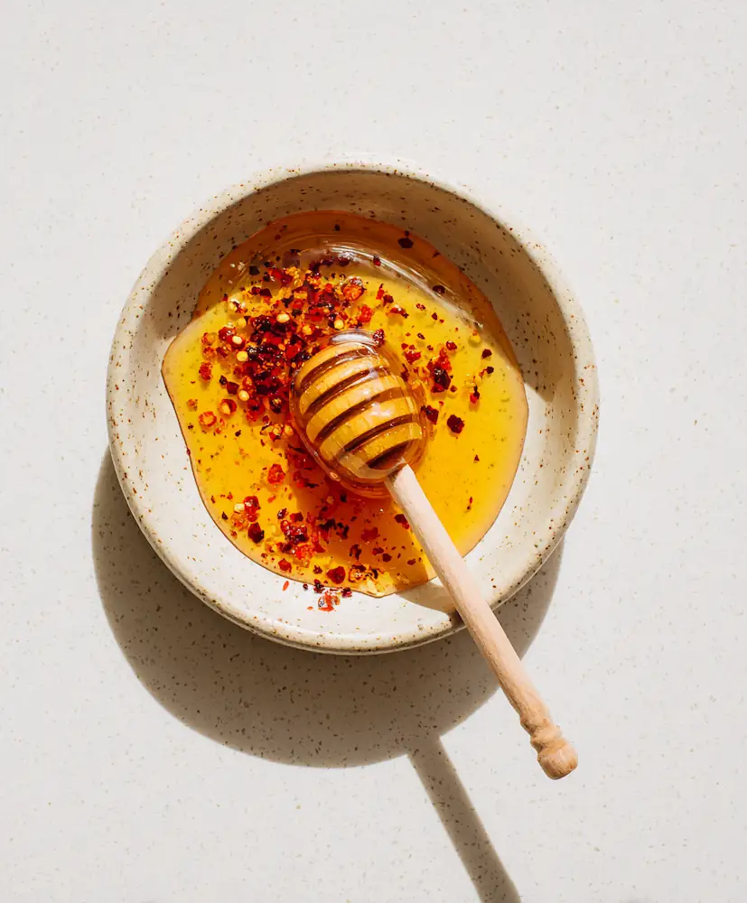 Honey, hot sauce, and chili flakes arranged in small bowls for hot honey sauce