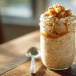 Creamy apple pie overnight oats in a mason jar topped with diced apples and cinnamon on a wooden table