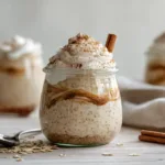 Cinnamon Roll Overnight Oats (No Bake) in a mason jar with cinnamon swirl and creamy yogurt icing on top