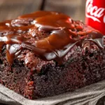 Moist Coca-Cola Cake with glossy chocolate glaze served on a student kitchen table