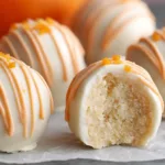 Close-up of No Bake Orange Creamsicle Truffles with pastel orange and white drizzle on parchment