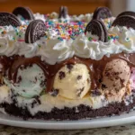 Homemade ice cream cake layered with chocolate cookies, vanilla, and chocolate ice cream topped with whipped cream and sprinkles.