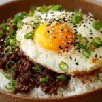 Beef bowl recipe with Korean ground beef over steamed rice, fried egg, sesame seeds, and scallions