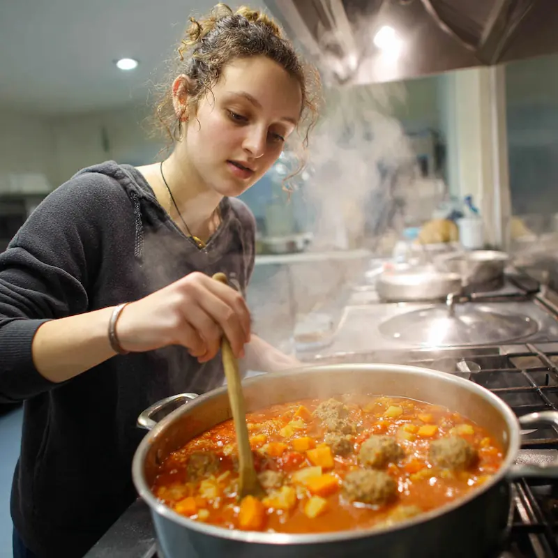 Cozy Mexican Meatball Soup (Albondigas) – Cheap & Comforting Student Dinner! 3 Student stirring pot of albondigas soup on stovetop with steam rising