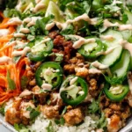 Healthy banh mi bowl with caramelized ground pork, pickled carrots and cucumber, cauliflower rice, fresh herbs and creamy sriracha sauce