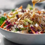 Chinese chicken salad with shredded chicken, romaine lettuce, carrots, red cabbage, dates, almonds, and creamy sesame-style dressing