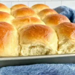 Soft and fluffy dinner rolls freshly baked in a pan with golden brown tops brushed with butter