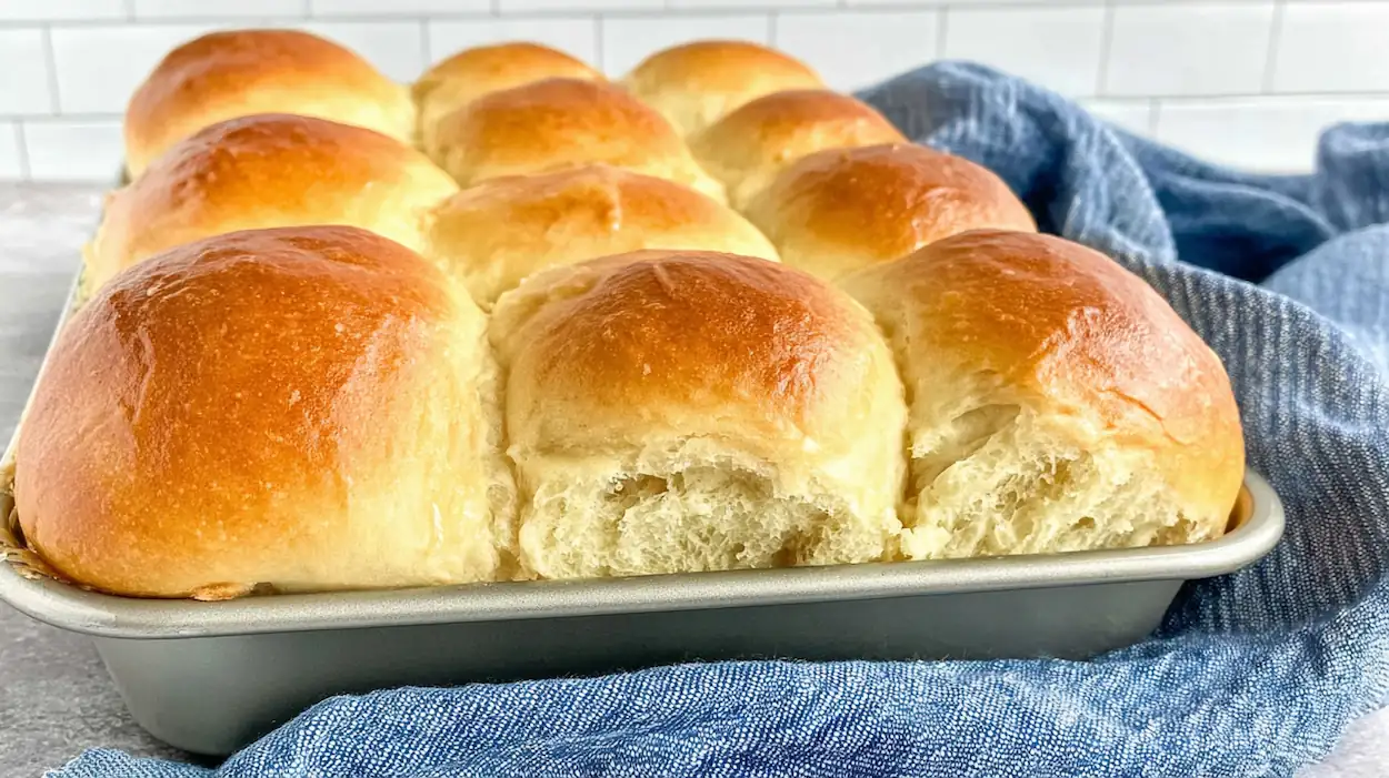 Soft and fluffy dinner rolls freshly baked in a pan with golden brown tops brushed with butter