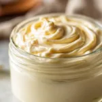 Easy homemade mayonnaise in a glass mason jar with fresh lemon on a wooden table
