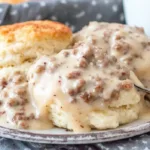 Creamy Southern sausage gravy poured over fluffy buttermilk biscuits on a plate, classic homemade sausage gravy recipe