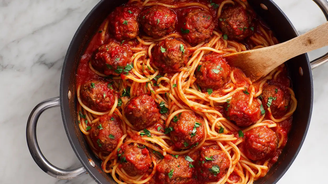 Spaghetti and meatballs served in a bowl with rich tomato sauce, parmesan cheese, and fresh parsley