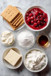Cherry Delight Dessert — The Creamy, No-Bake Classic Everyone Loves 5 Overhead flat lay of ingredients for cherry delight dessert including graham crackers, cream cheese, powdered sugar, Cool Whip, melted butter, vanilla extract, and canned cherry pie filling arranged neatly on a marble surface.