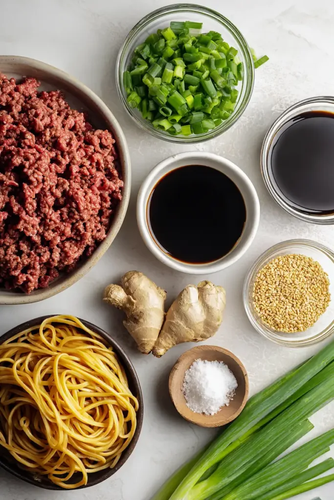 Easy Mongolian Ground Beef Noodles (Quick, Budget-Friendly Dinner) 3 Ingredients for Mongolian ground beef noodles including ground beef, soy sauce, brown sugar, garlic, ginger, noodles, and green onions arranged on a countertop
