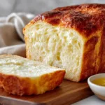 Close-up of sliced easy 2-ingredient cottage cheese bread with a golden crust and fluffy interior on a wooden board.