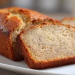 Easy One-Bowl Banana Bread Recipe (Moist & Foolproof) Moist one-bowl banana bread sliced on a white plate, homemade banana bread recipe with golden crust