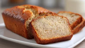 Moist one-bowl banana bread sliced on a white plate, homemade banana bread recipe with golden crust
