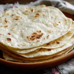 Easy Sourdough Discard Tortillas (Soft & Chewy 4 Ingredient Recipe) Stack of soft homemade sourdough discard tortillas with golden brown spots on a plate, ready for tacos.