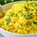 Fluffy golden turmeric rice in a white bowl, garnished with fresh parsley and served warm in natural light
