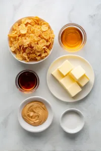 Easy Corn Flake Cookies (No Bake & Budget-Friendly) 5 Flat lay of ingredients for easy corn flake cookies including cornflakes, peanut butter, sugar, butter, corn syrup, and vanilla.