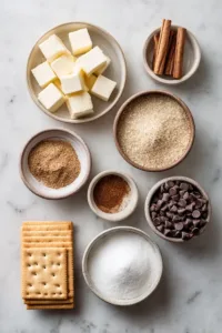 Churro Toffee Recipe (Easy Disneyland Copycat Treat) 5 Flat lay of churro toffee ingredients including saltine crackers, butter, brown sugar, chocolate chips, cinnamon, and granulated sugar on a light marble surface