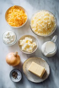 Ingredients for cracker barrel hashbrown casserole including frozen hashbrowns, cheddar cheese, sour cream, butter, onion, and cream of chicken soup