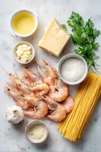 Easy Shrimp Alfredo Recipe (High-Protein, Family-Friendly Dinner) 5 Raw shrimp, fettuccine pasta, heavy cream, butter, garlic, and Parmesan cheese arranged on a light marble surface for Shrimp Alfredo recipe.