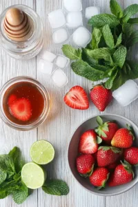 Healthy Strawberry Mint Mocktail 5 Fresh ingredients for a healthy strawberry mint mocktail including strawberries, mint leaves, lime, honey and sparkling water.