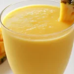 Creamy pineapple mango smoothie in a glass with tropical fruits, healthy refreshing smoothie recipe