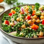 Fresh kale quinoa salad with chickpeas, vegetables, and lemon vinaigrette dressing in a bowl