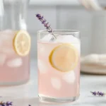 Lavender lemonade recipe served over ice with lemon slices in a bright modern American kitchen.