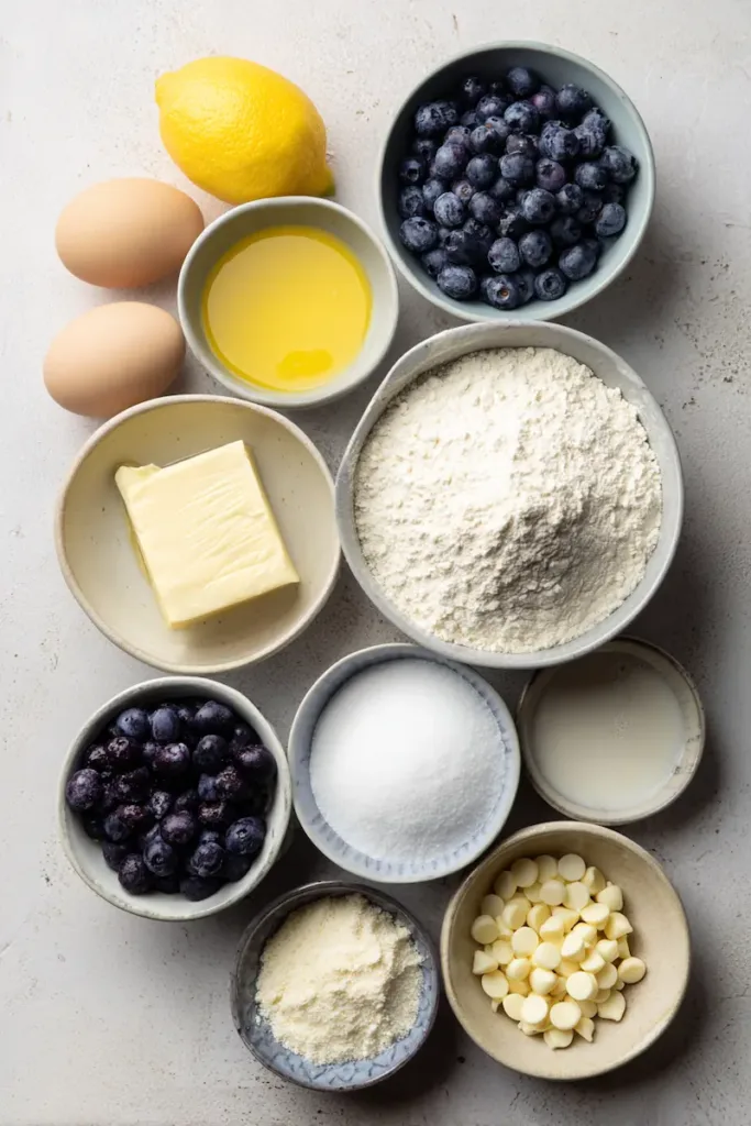 Ingredients for Easy Lemon Blueberry Cookies including flour, cornstarch, baking soda, baking powder, salt, butter, sugars, egg, lemon, vanilla, blueberries, white chocolate chips, and powdered sugar.